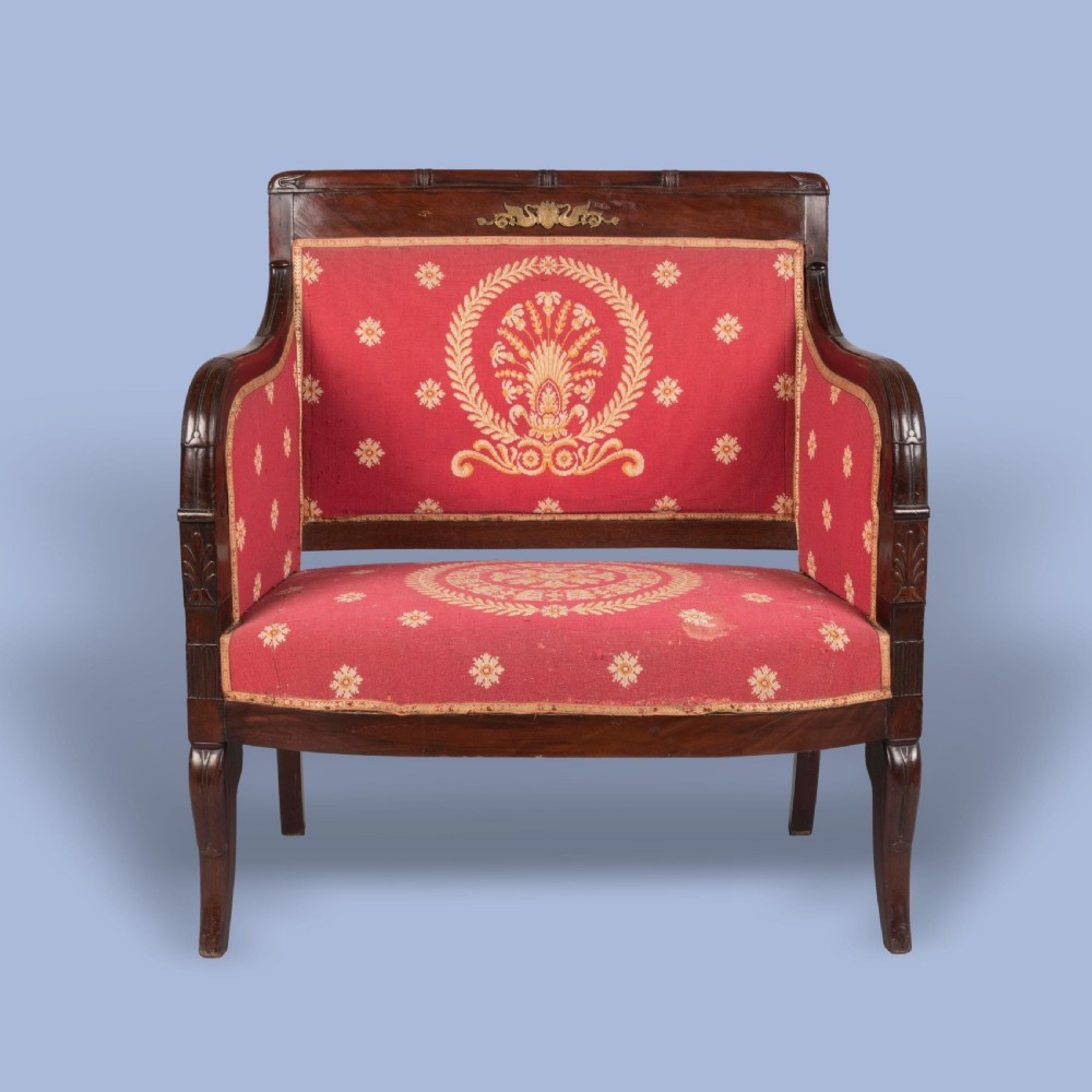 An Empire style dark mahogany fauteuil armchair upholstered in crimson patterned textile with gilt metal crest mounts. View II