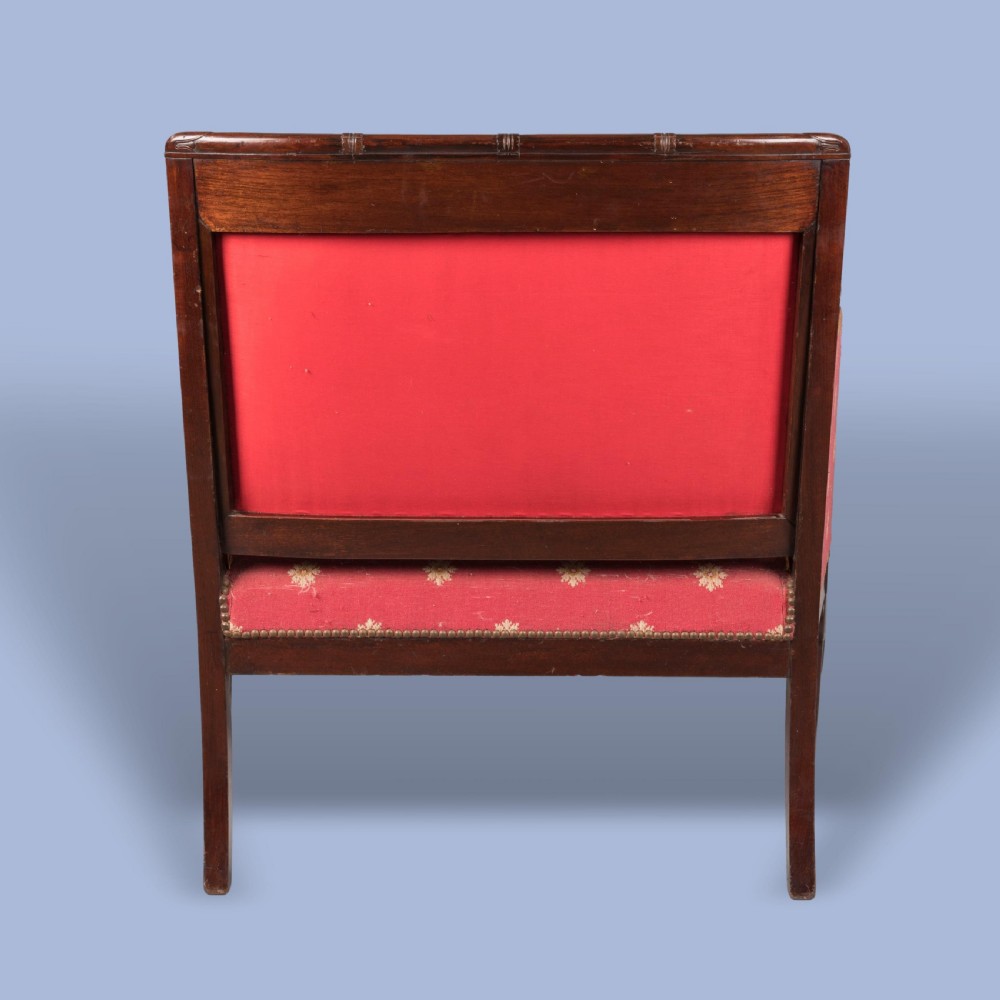 An Empire style dark mahogany fauteuil armchair upholstered in crimson patterned textile with gilt metal crest mounts. View III