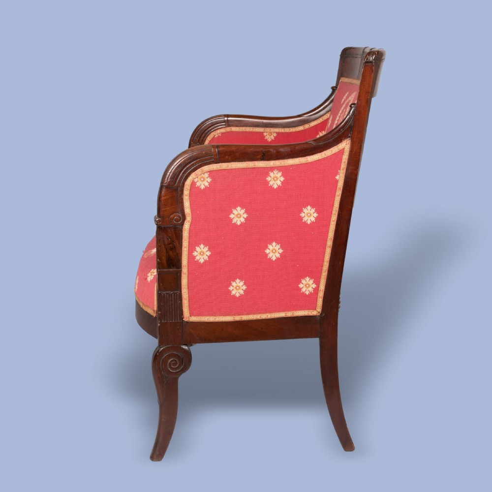An Empire style dark mahogany fauteuil armchair upholstered in crimson patterned textile with gilt metal crest mounts. View V