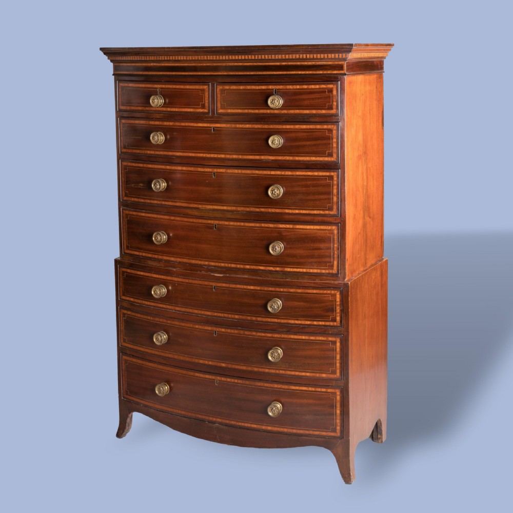 A George III bow-fronted mahogany tallboy chest-on-chest with brass pull handles and geometric line inlay.