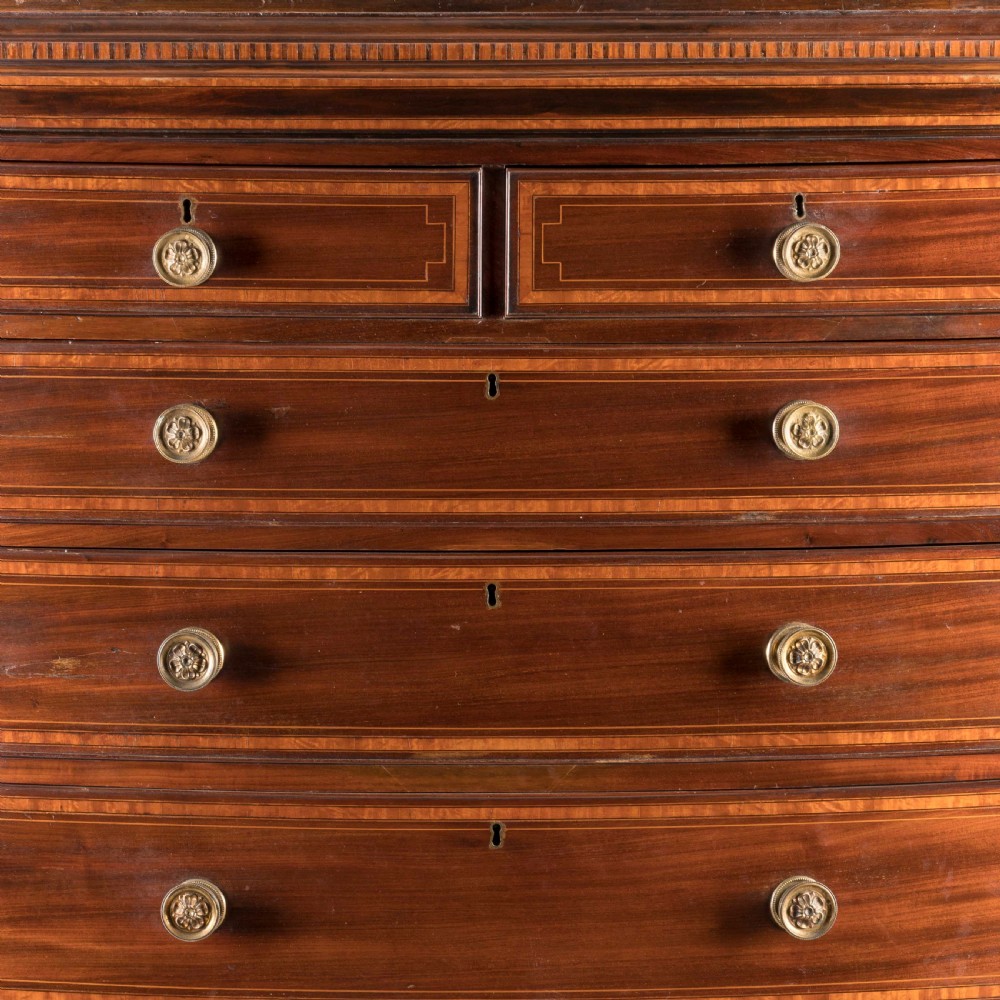 A George III bow-fronted mahogany tallboy chest-on-chest with brass pull handles and geometric line inlay. View II