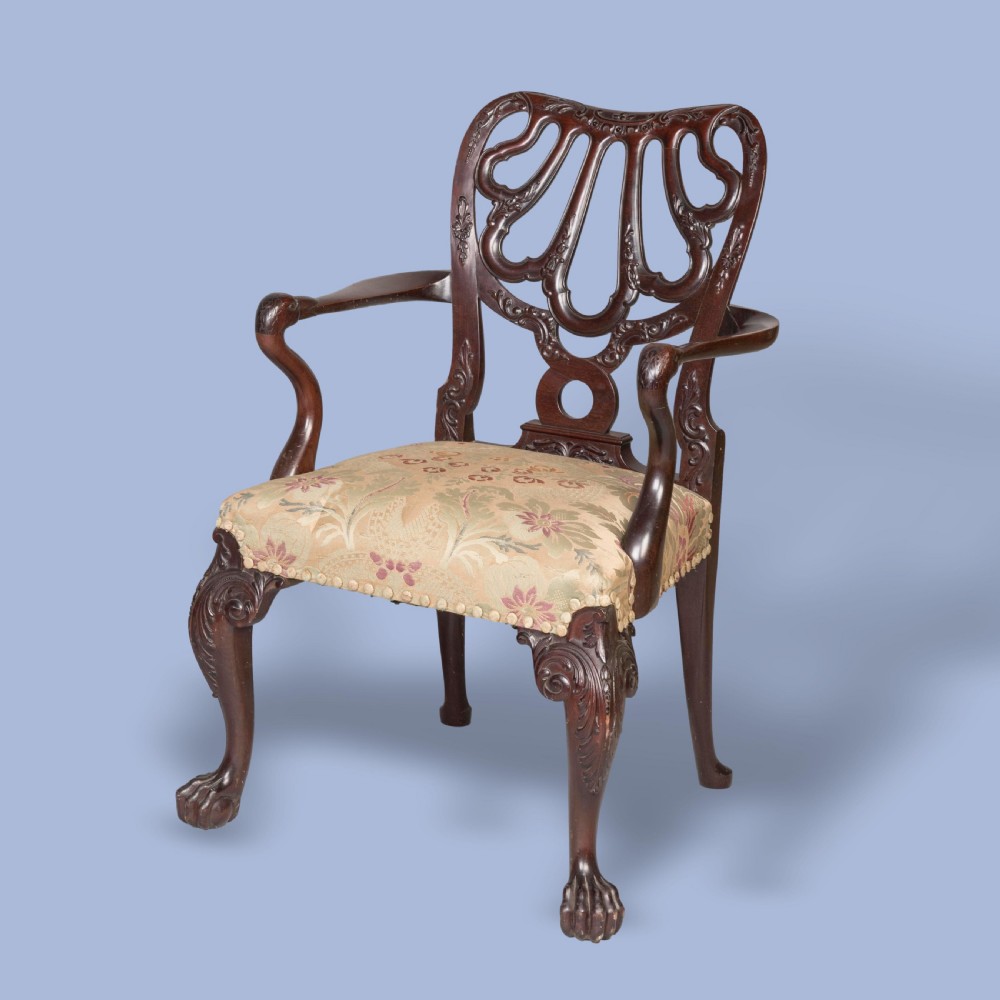 A dark mahogany open armchair featuring a carved pierced back splat, floral pattern upholstered seat, and cabriole front legs with ball-and-claw feet.