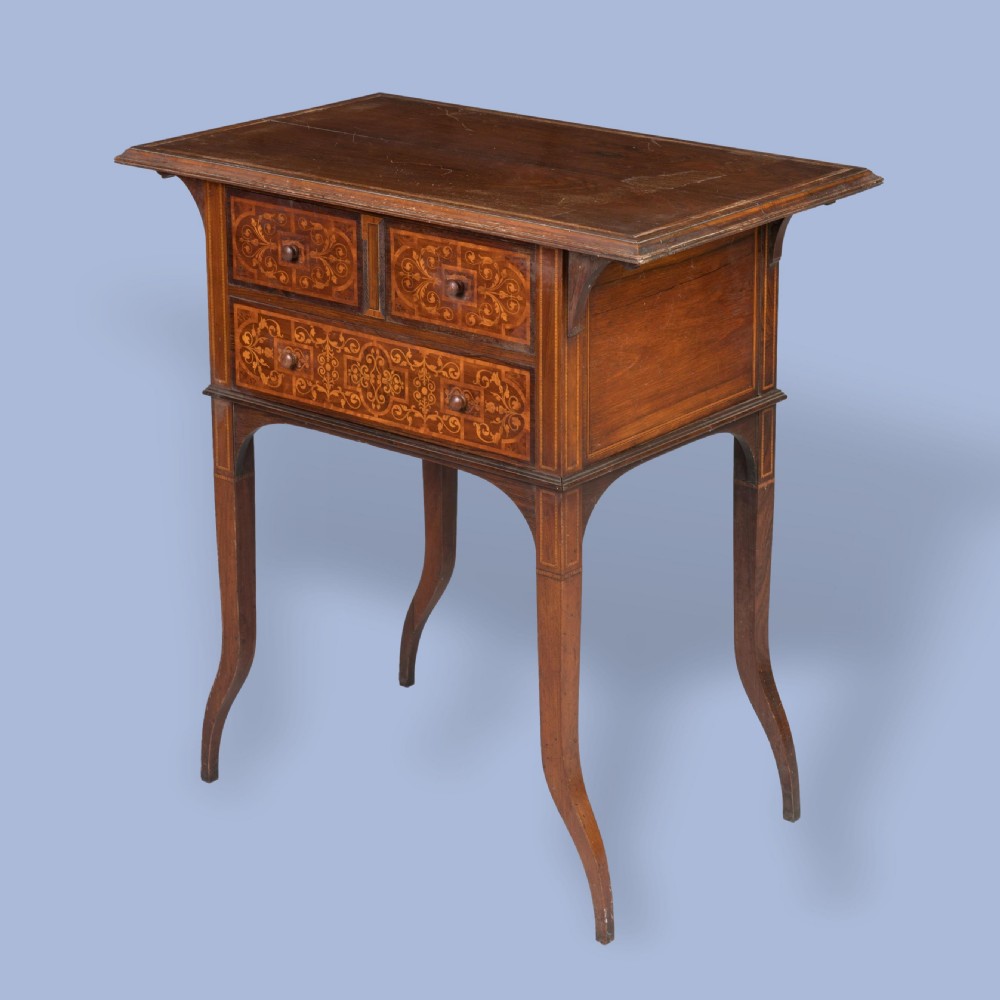 An Aesthetic Movement dark wood side table with detailed floral marquetry inlays on the drawers and slender curved legs.