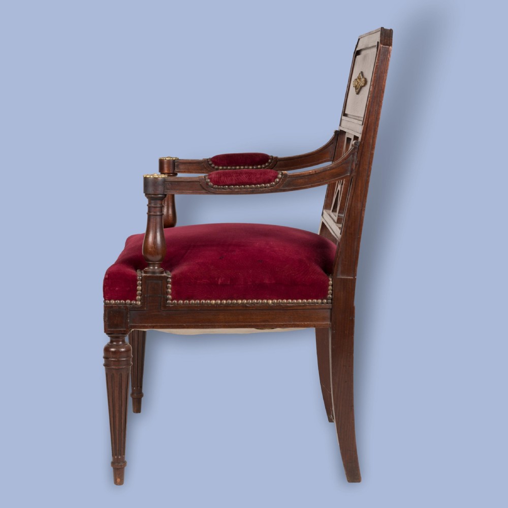 A pair of French Consulate style mahogany armchairs with red velvet upholstery, fluted front legs, and decorative brass star mounts. View VI