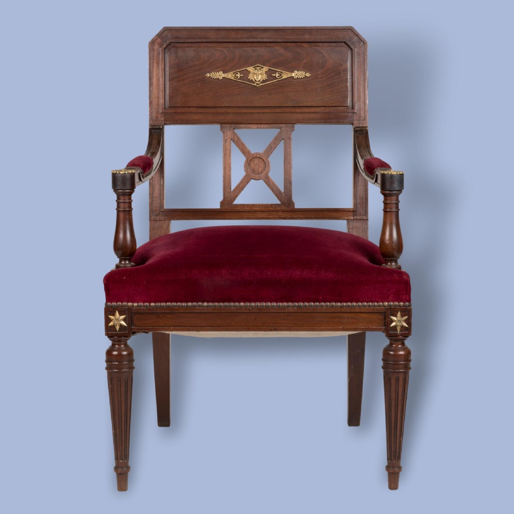 A pair of French Consulate style mahogany armchairs with red velvet upholstery, fluted front legs, and decorative brass star mounts. View VII