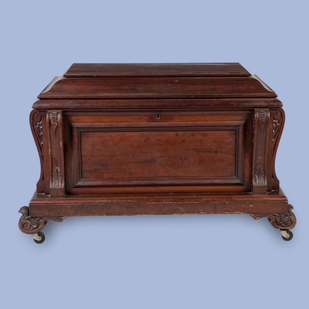 A William IV mahogany sarcophagus cellarette with carved scroll corner pilasters, panelled sides, and castors. View II