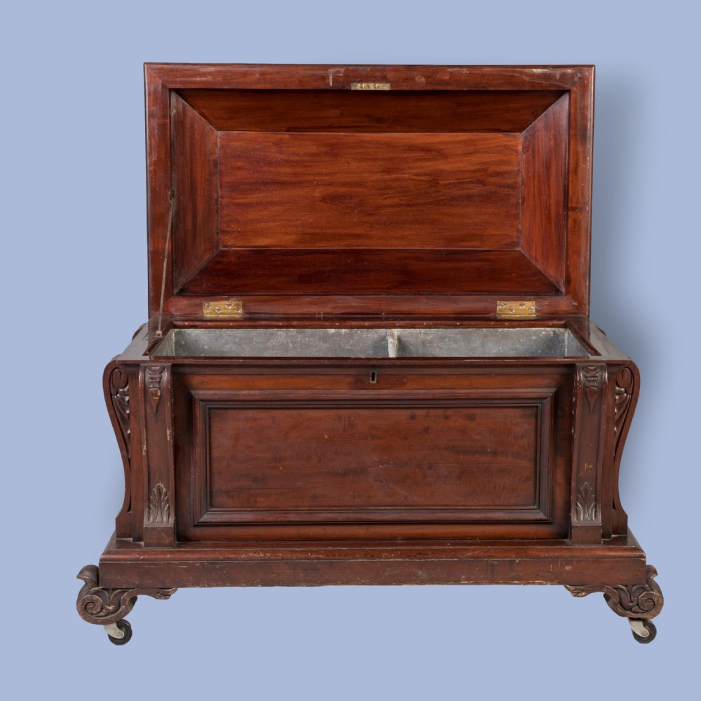 A William IV mahogany sarcophagus cellarette with carved scroll corner pilasters, panelled sides, and castors. View IV