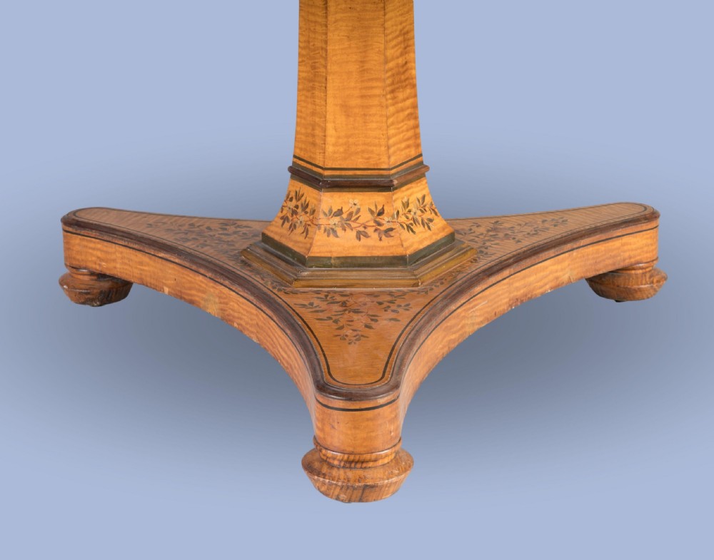 A Regency period circular centre table crafted from light sycamore with hand-painted floral borders resting on a central pedestal and triform base. View IV