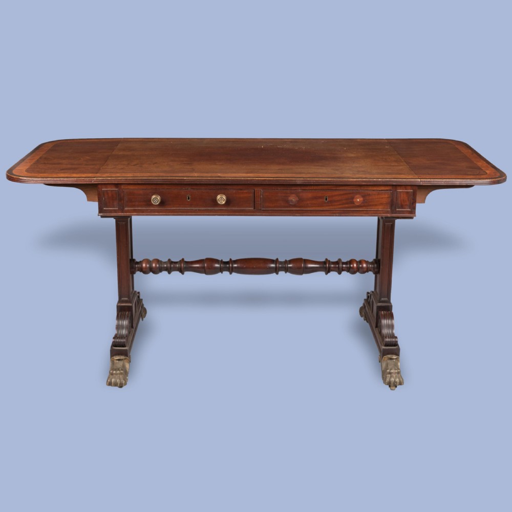 A Regency period dark mahogany sofa table featuring two frieze drawers, drop leaves, a turned stretcher, and splayed legs with brass paw feet. View II