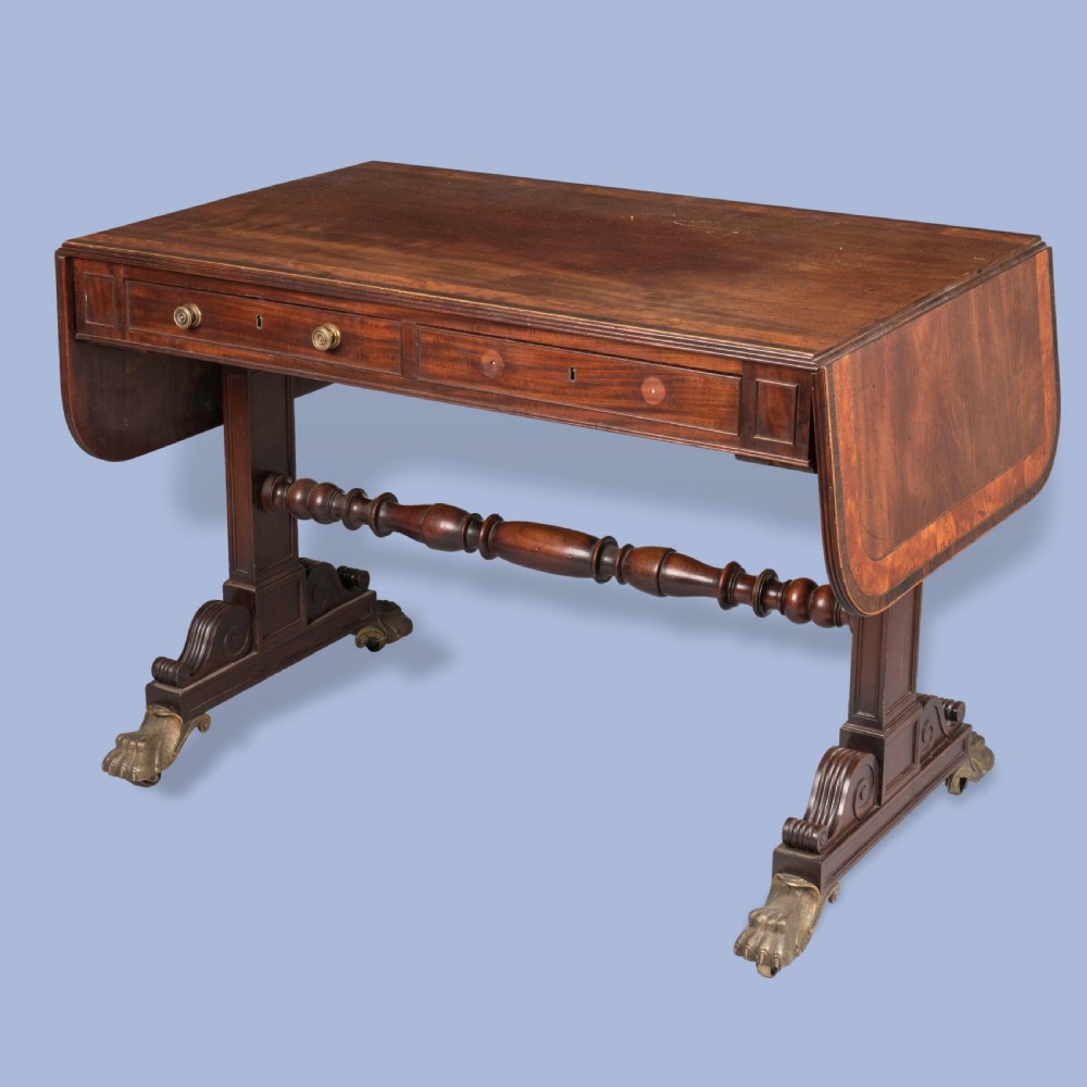 A Regency period dark mahogany sofa table featuring two frieze drawers, drop leaves, a turned stretcher, and splayed legs with brass paw feet. View III
