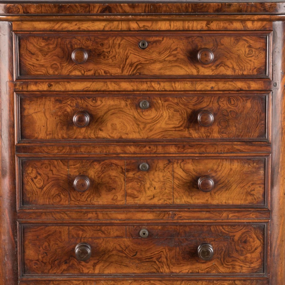 A tall Victorian burr walnut Wellington chest featuring seven graduated drawers, turned knobs, a locking side bar, and a plinth base. View IV