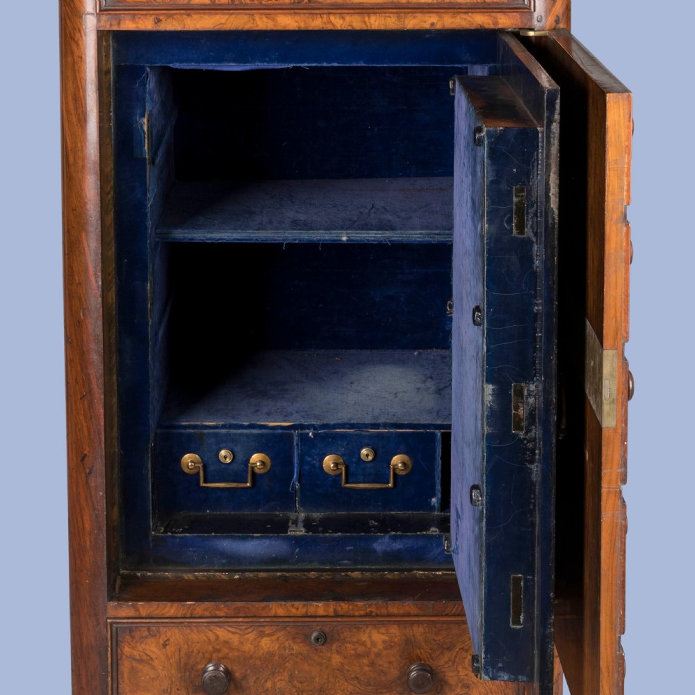 A tall Victorian burr walnut Wellington chest featuring seven graduated drawers, turned knobs, a locking side bar, and a plinth base. View V