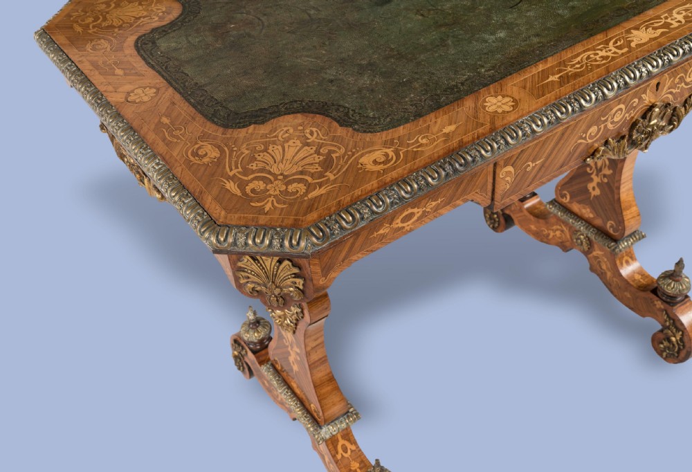 An ornate 19th-century French style marquetry writing table featuring a green leather top, gilt-bronze mounts, and scrolled end supports. View III
