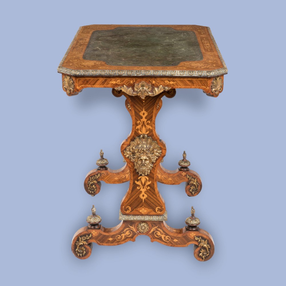 An ornate 19th-century French style marquetry writing table featuring a green leather top, gilt-bronze mounts, and scrolled end supports. View VI
