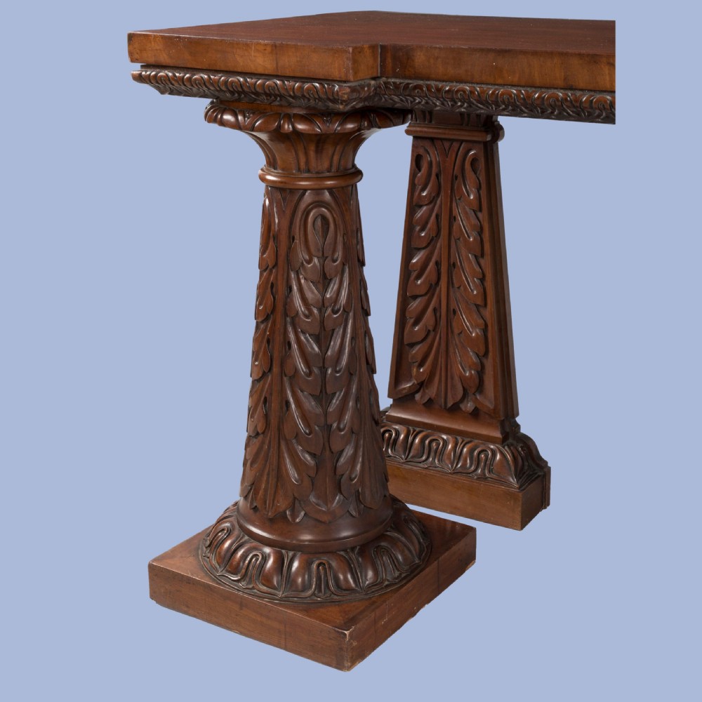 A William IV mahogany serving table featuring a rectangular top, gadrooned edge trimming, and acanthus leaf carved column supports on plinth bases. View V