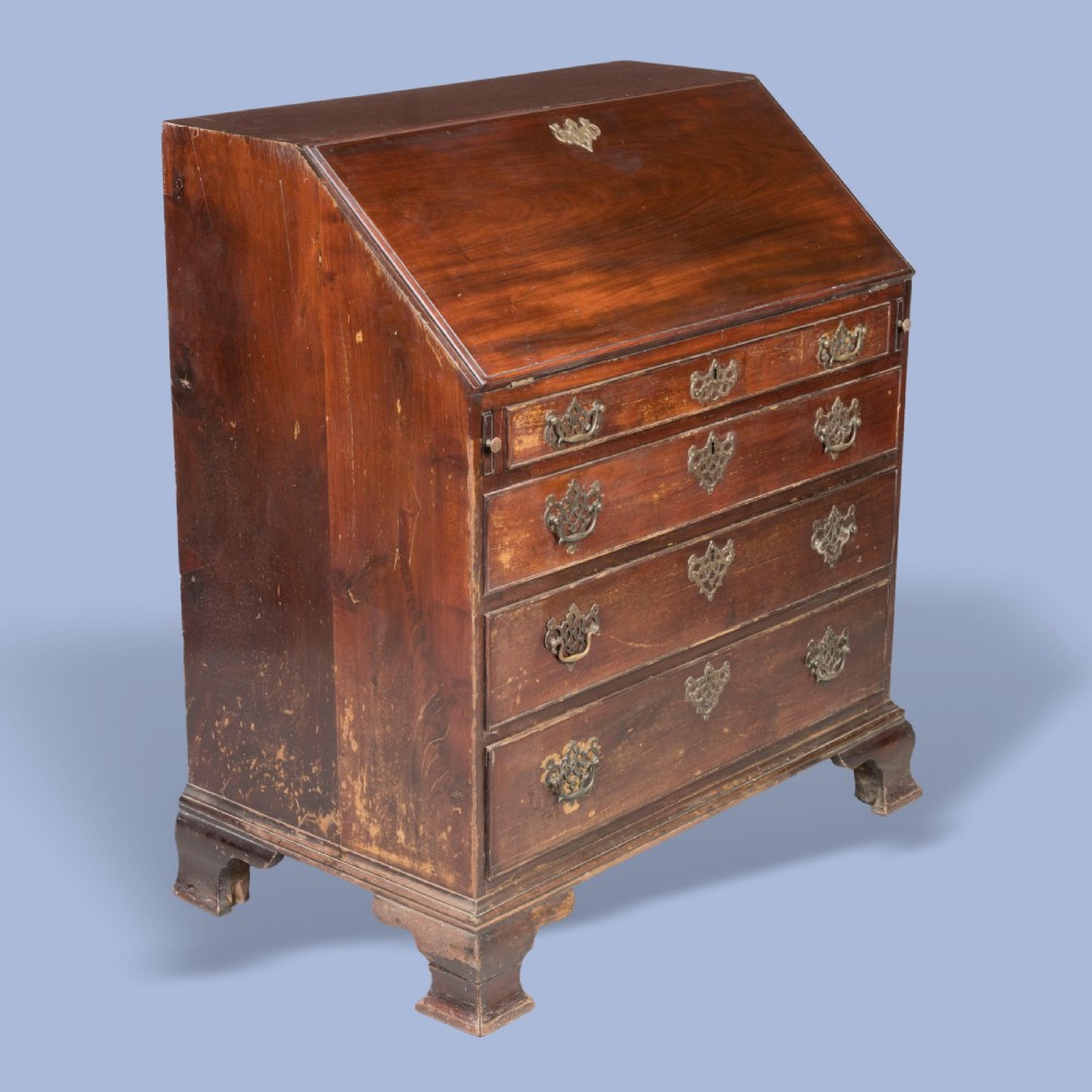 A Georgian mahogany slant-front writing bureau featuring four graduated drawers with decorative brass handles and bracket feet.