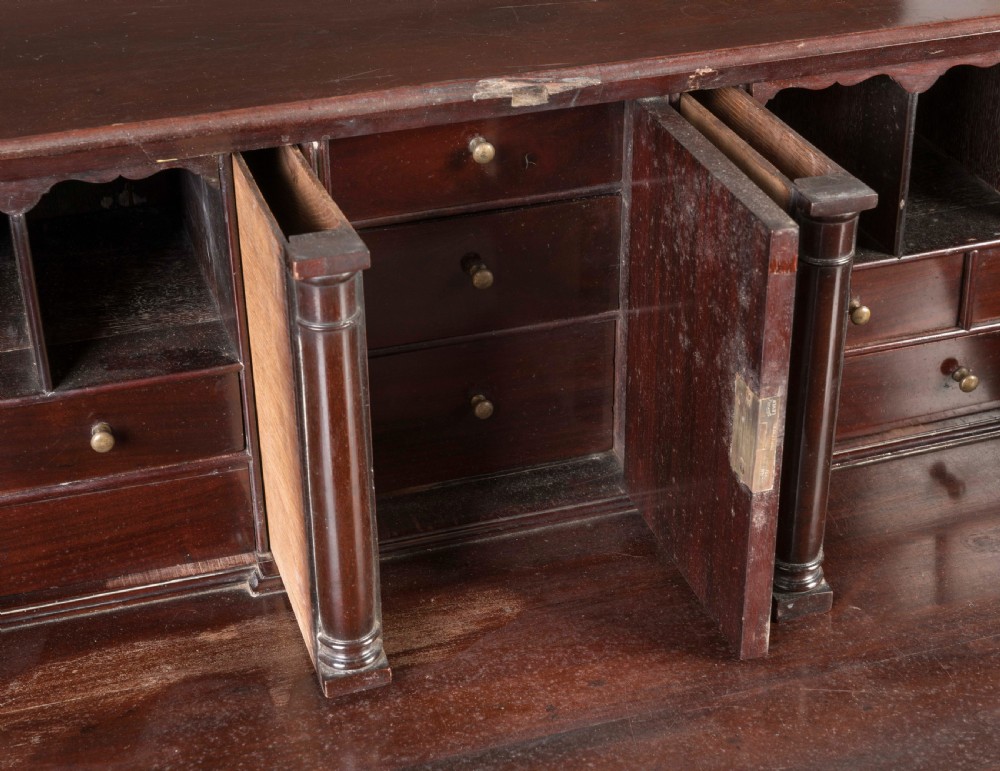 A Georgian mahogany slant-front writing bureau featuring four graduated drawers with decorative brass handles and bracket feet. View V
