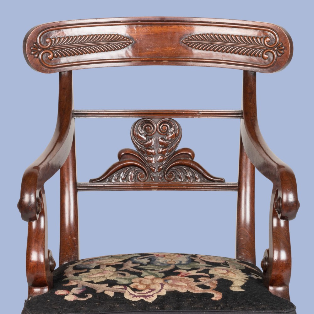 A William IV mahogany armchair featuring a carved top rail, curved scroll armrests, turned front legs on brass castors, and floral tapestry seat upholstery. View IV