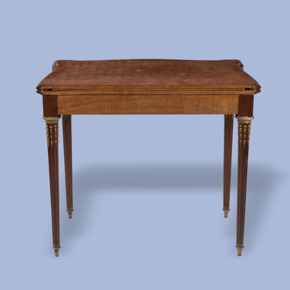A rectangular Louis XVI style card table featuring geometric parquetry wood veneers, fluted tapering legs, and gilded ormolu mounts. View III