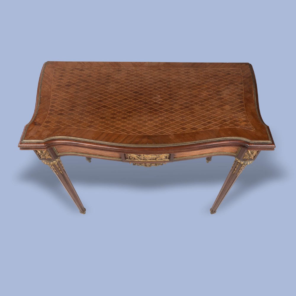 A rectangular Louis XVI style card table featuring geometric parquetry wood veneers, fluted tapering legs, and gilded ormolu mounts. View VII