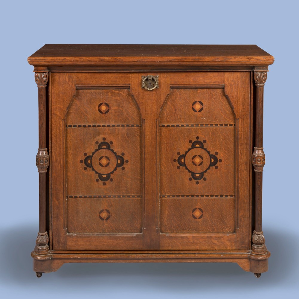 An antique Victorian Gothic Revival oak folio cabinet featuring geometric timber inlay on twin panel doors beneath an adjustable slatted display frame. View II