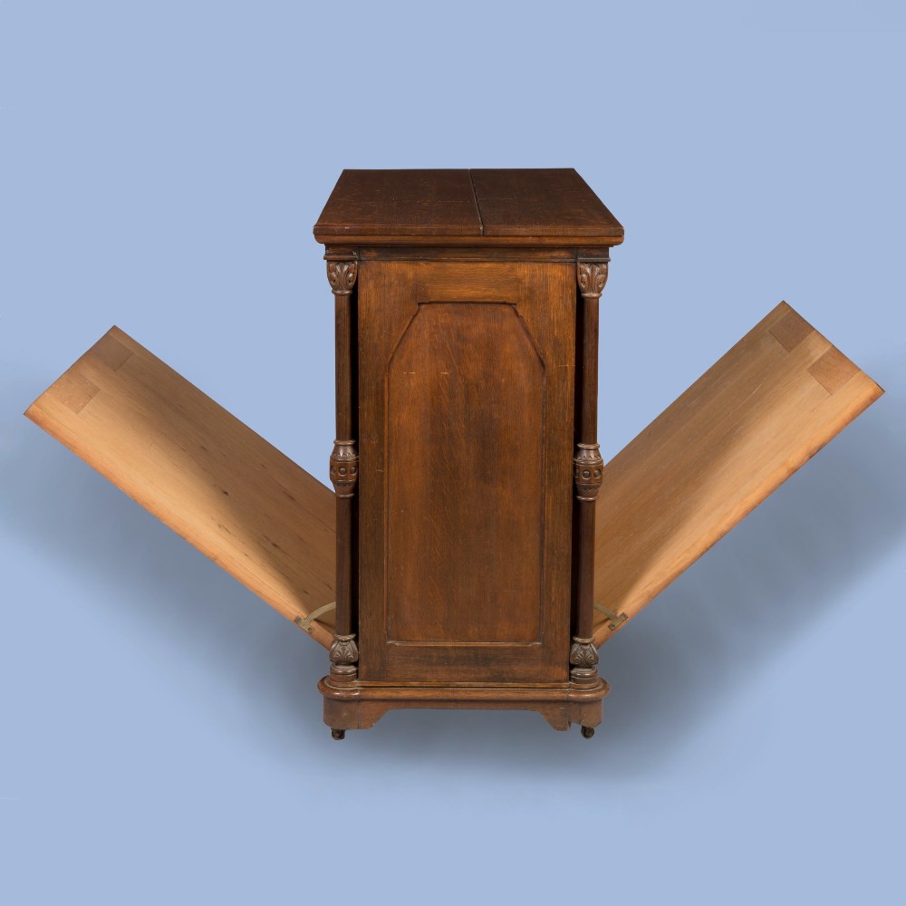 An antique Victorian Gothic Revival oak folio cabinet featuring geometric timber inlay on twin panel doors beneath an adjustable slatted display frame. View V