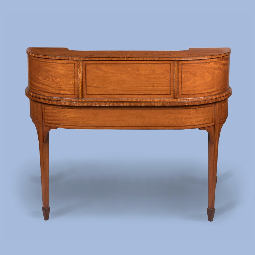 An Edwardian satinwood Carlton House desk featuring a curved rear superstructure with drawers, a leather writing surface, and square tapered legs. View III