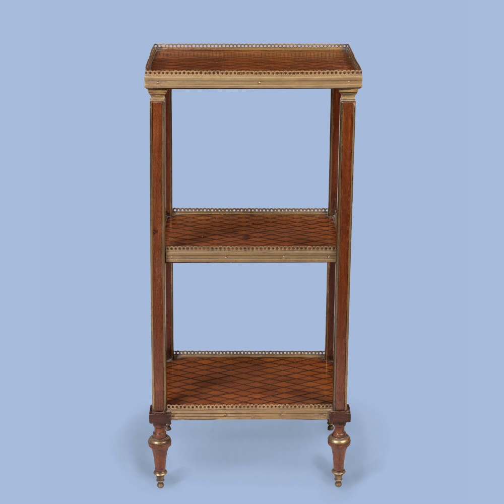 A three-tier rectangular wooden etagere featuring geometric parquetry shelves, pierced brass gallery rims, fluted corner supports, and brass-capped turned feet. View II