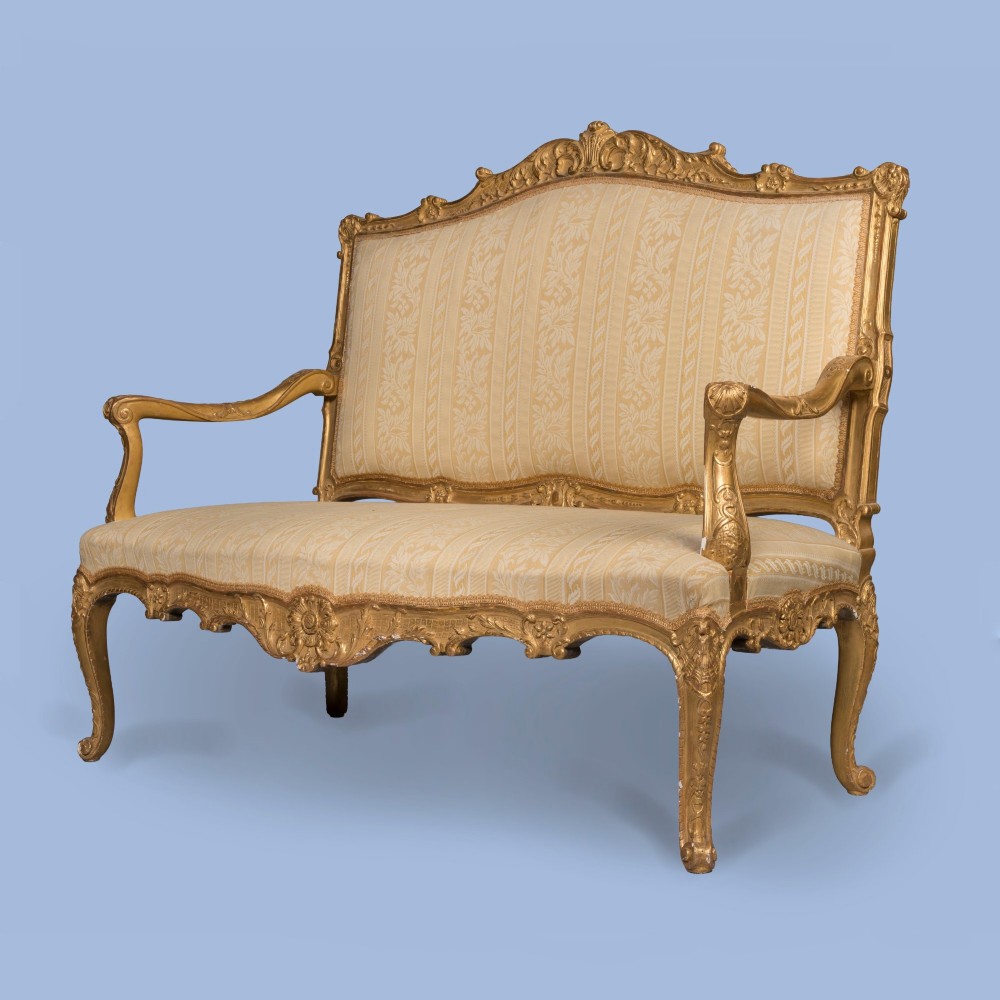 A French Louis XV style giltwood canape featuring carved floral cresting, cabriole legs, and light gold striped damask upholstery. View II