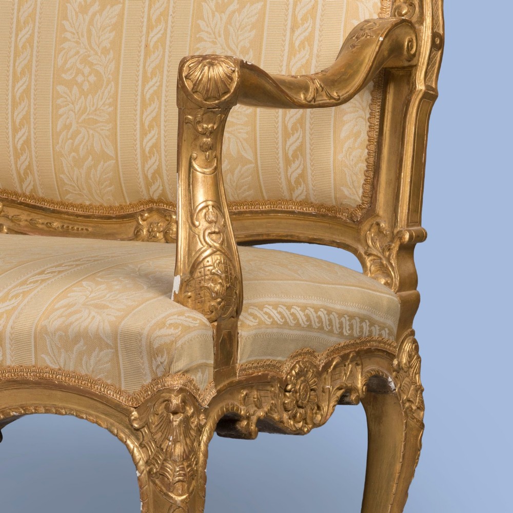 A French Louis XV style giltwood canape featuring carved floral cresting, cabriole legs, and light gold striped damask upholstery. View III