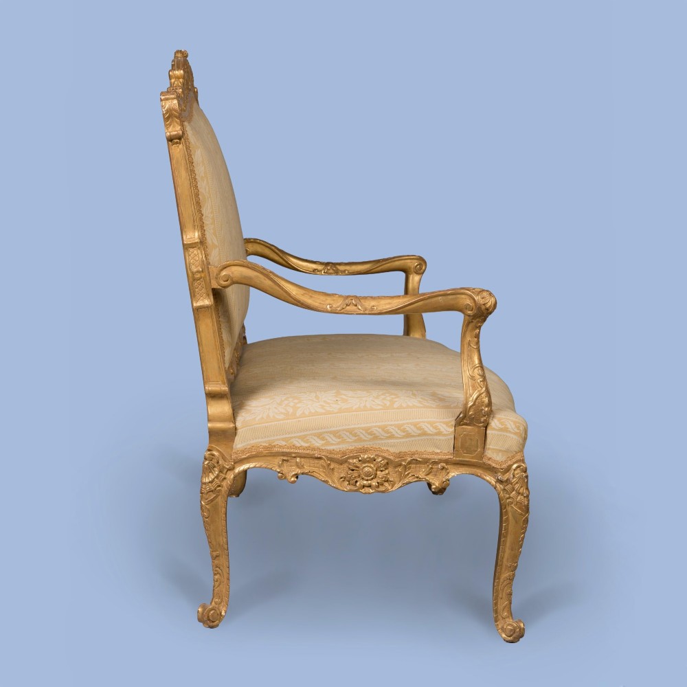 A French Louis XV style giltwood canape featuring carved floral cresting, cabriole legs, and light gold striped damask upholstery. View VI