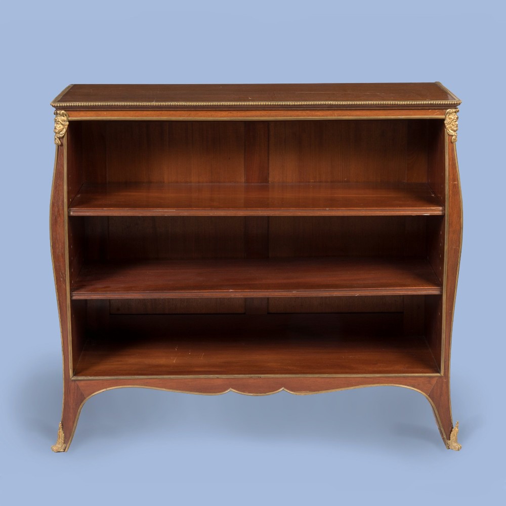 A low mahogany open bookcase featuring curved sides, adjustable shelves, a shaped apron, and gilt-bronze ormolu mounts on the corners and feet. View III