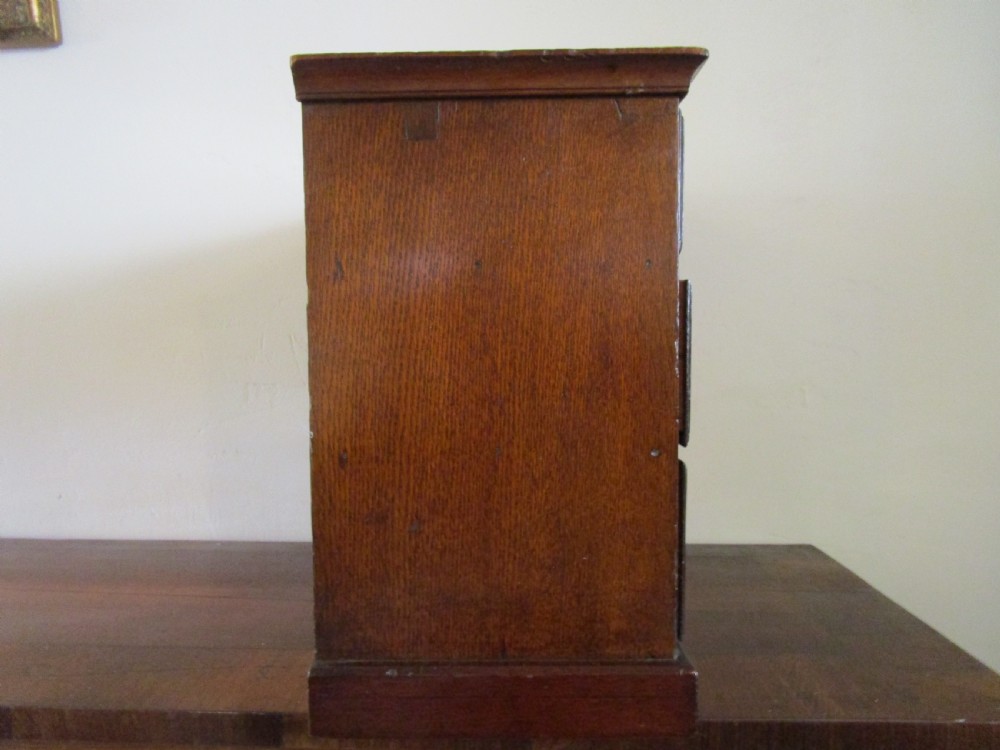 A dark mahogany miniature chest of drawers featuring two short and two long drawers with turned white knobs and brass escutcheons. View III