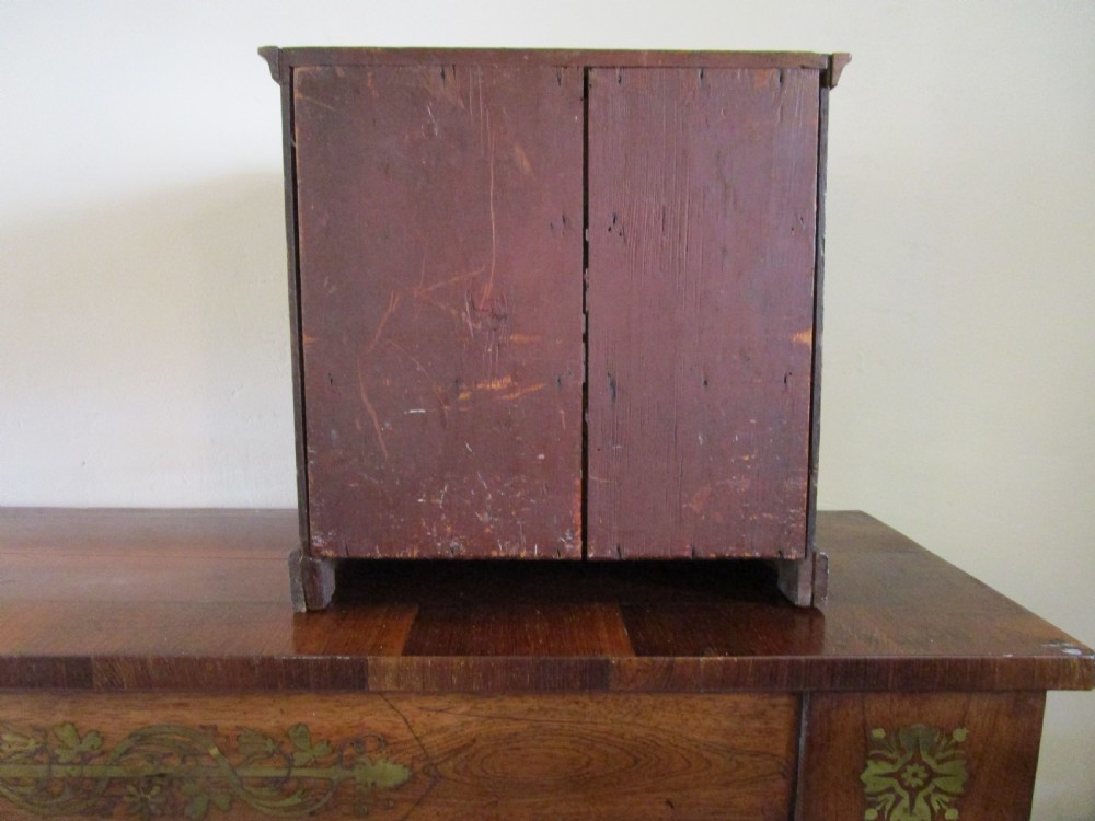 A dark mahogany miniature chest of drawers featuring two short and two long drawers with turned white knobs and brass escutcheons. View X