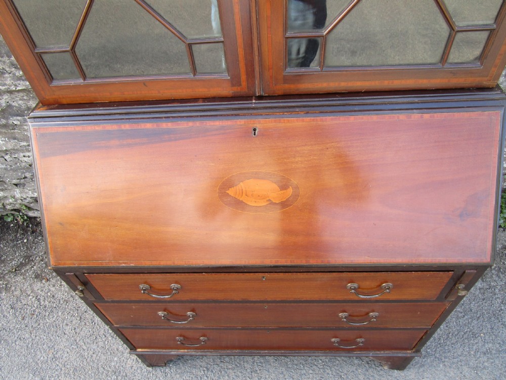 An antique mahogany bureau bookcase with a swan-neck pediment, geometric glazed cabinet doors, an inlaid fall-front writing slope, and three lower drawers. View V