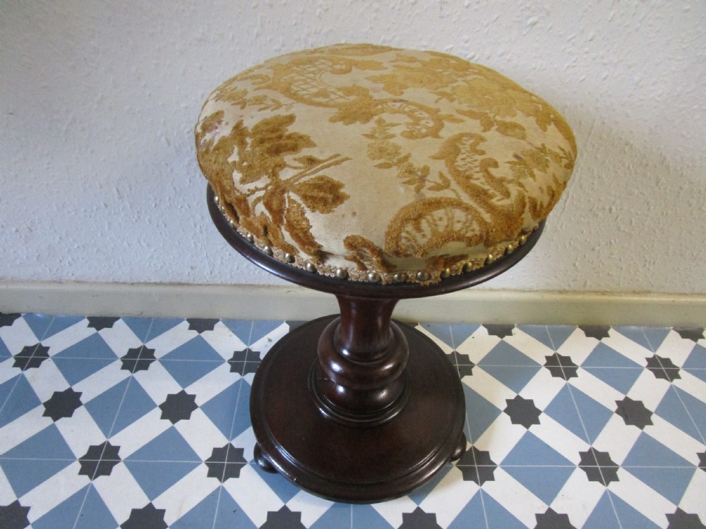 A Victorian dark wood revolving piano stool featuring a circular patterned velvet cushion trimmed with brass studs set atop a turned pedestal base. View III
