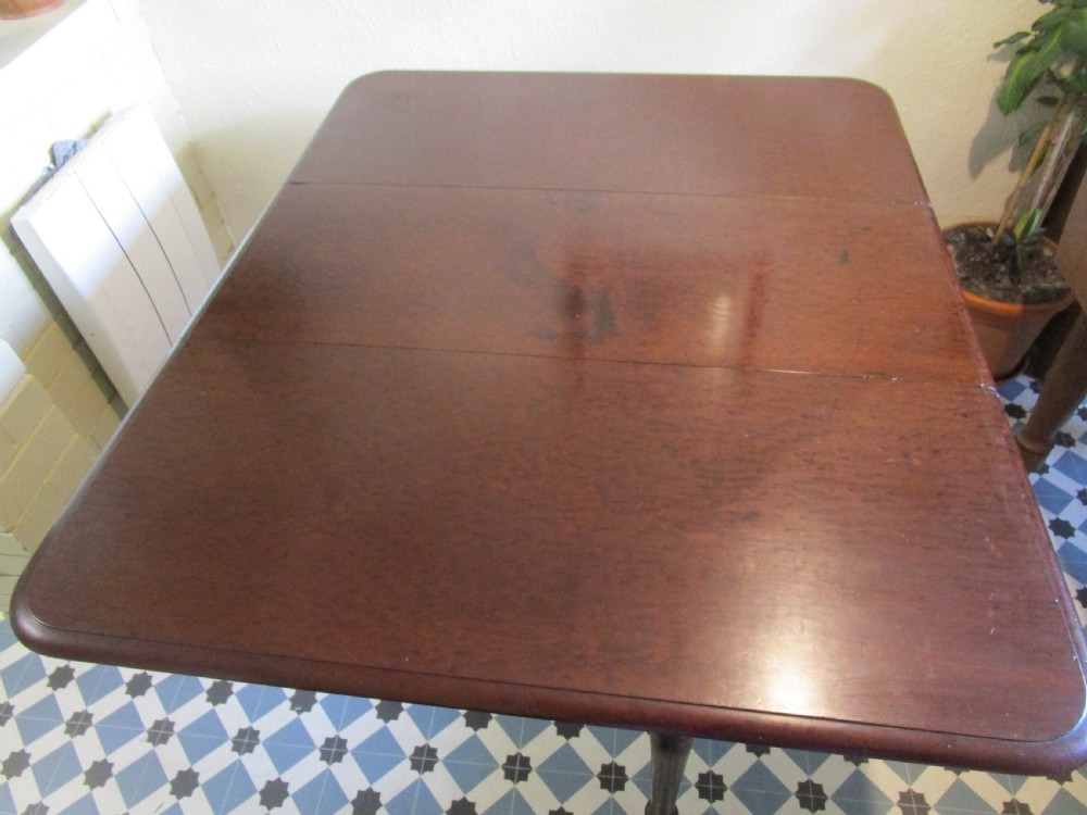 A Georgian plum pudding mahogany drop-leaf dining table with turned legs and brass castors. View III