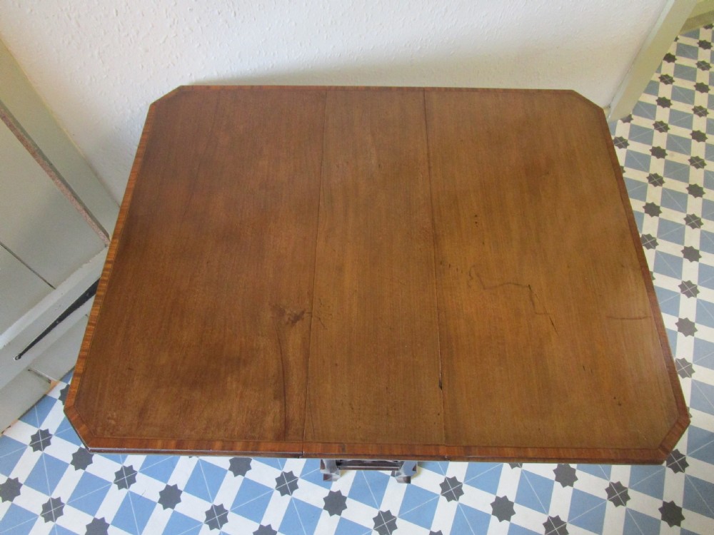 A compact mahogany Sutherland drop-leaf table with curved legs, a lower shelf, and small brass castors. View II