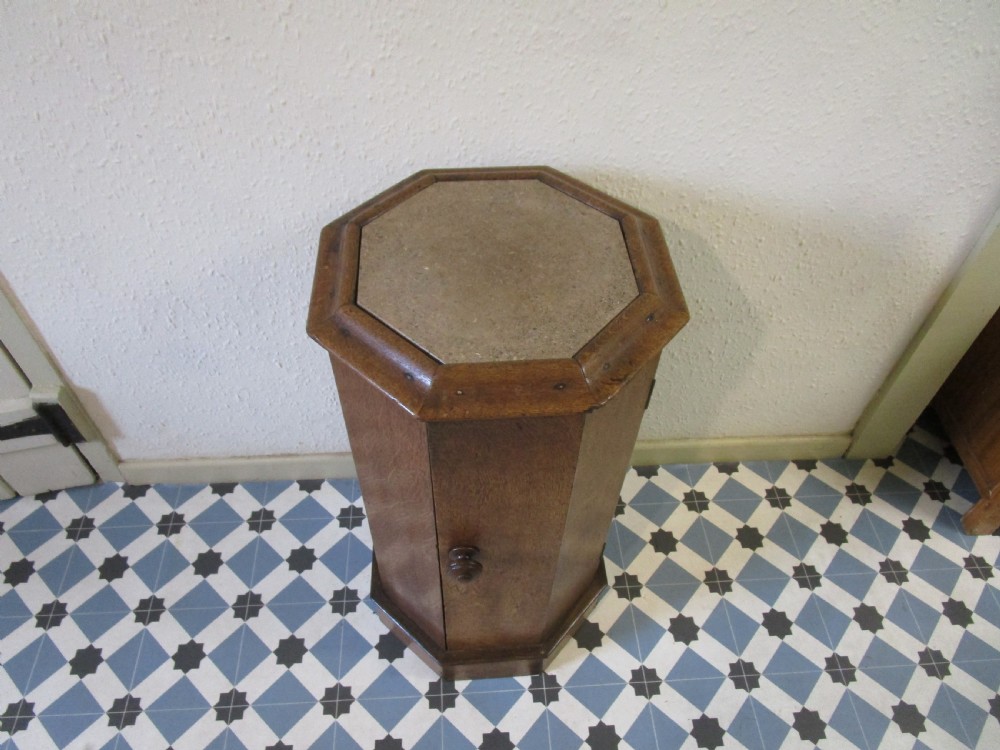 An octagonal antique oak bedside pot cupboard featuring a moulded top, single hinged door with a turned wooden knob, and a solid plinth base. View II