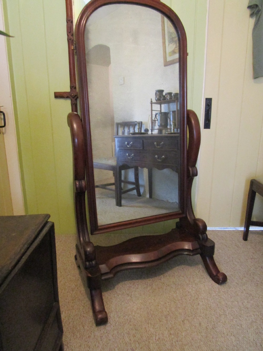 A Victorian mahogany cheval mirror featuring an arched glass frame supported by curved uprights on a shaped base with splayed feet.