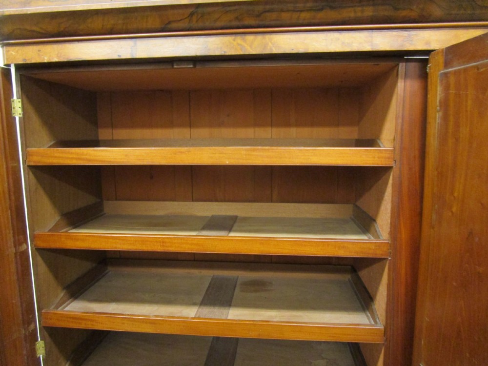 A Victorian three-door burr walnut compactum wardrobe featuring a full-length central mirror and arched panel doors set on a plinth base. View III