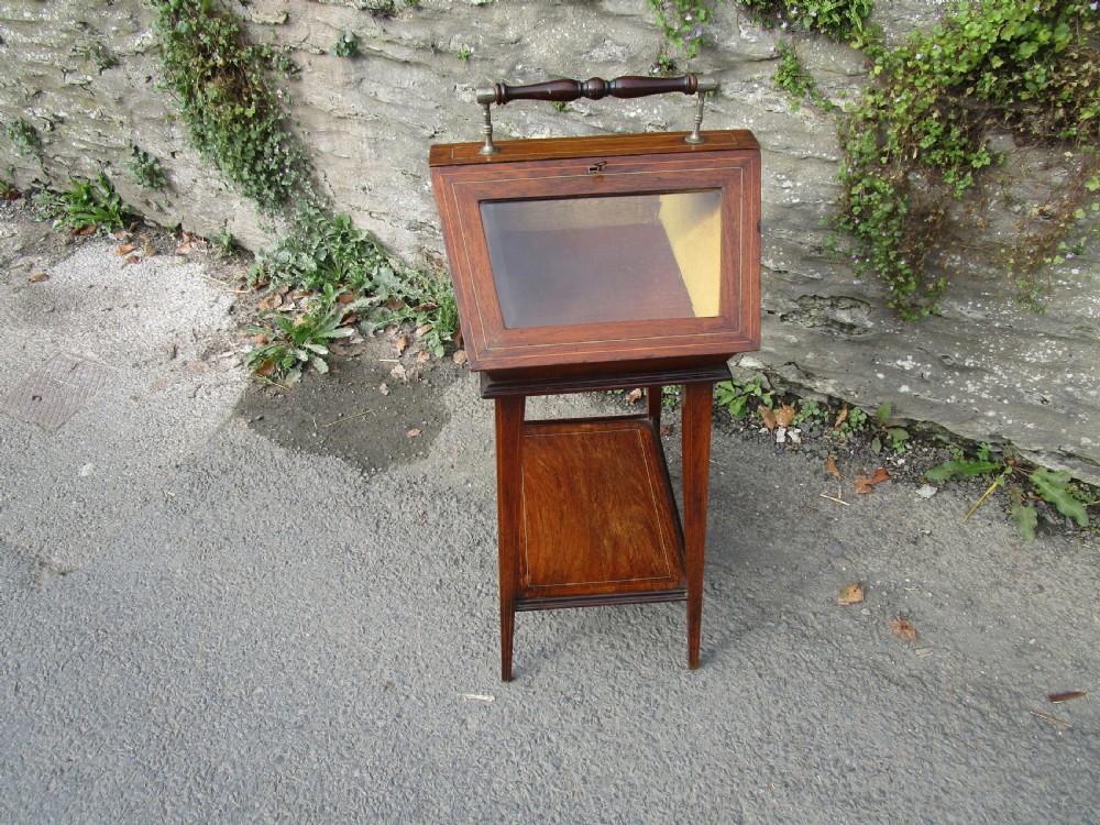 An antique mahogany bijouterie table featuring a pitched glazed display lid with a central turned handle, boxwood inlay, and a lower shelf. View II