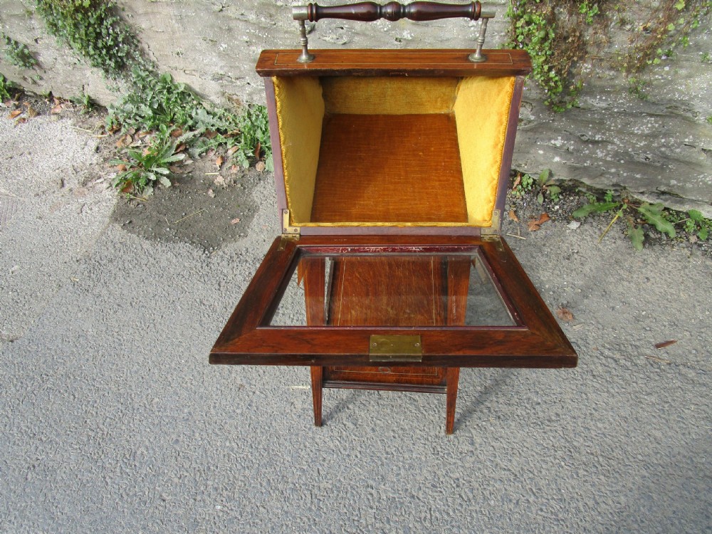 An antique mahogany bijouterie table featuring a pitched glazed display lid with a central turned handle, boxwood inlay, and a lower shelf. View III