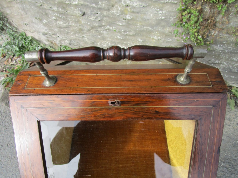 An antique mahogany bijouterie table featuring a pitched glazed display lid with a central turned handle, boxwood inlay, and a lower shelf. View IV