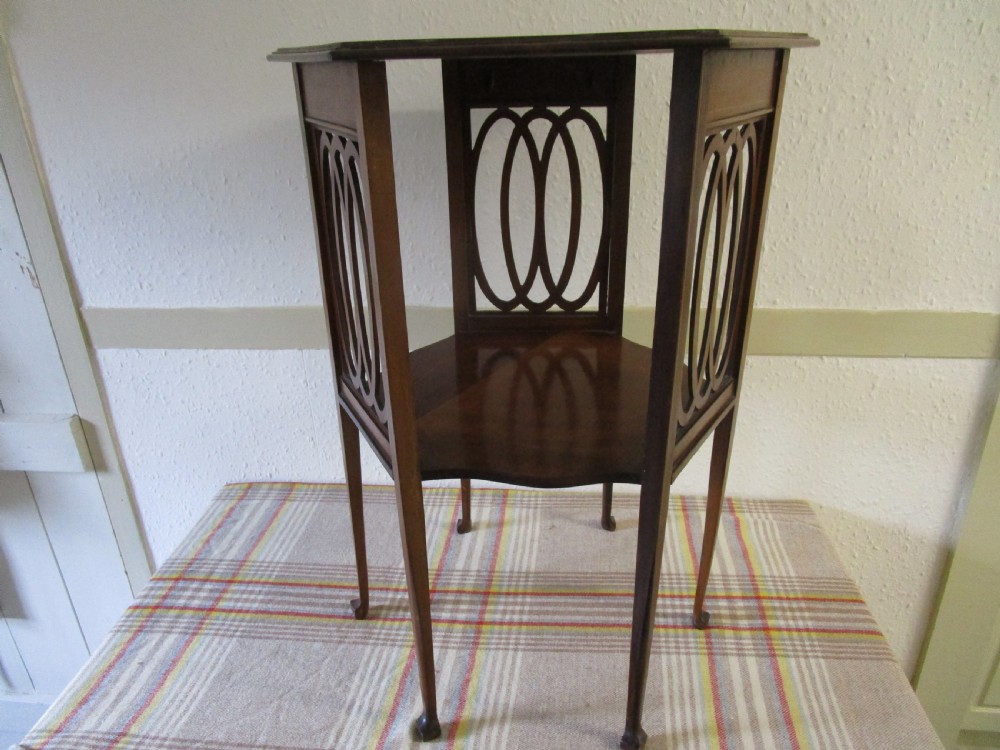A warm brown mahogany occasional table featuring pierced fretwork side panels, a lower tier, and slender tapered legs.