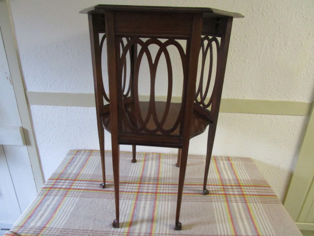 A warm brown mahogany occasional table featuring pierced fretwork side panels, a lower tier, and slender tapered legs. View II