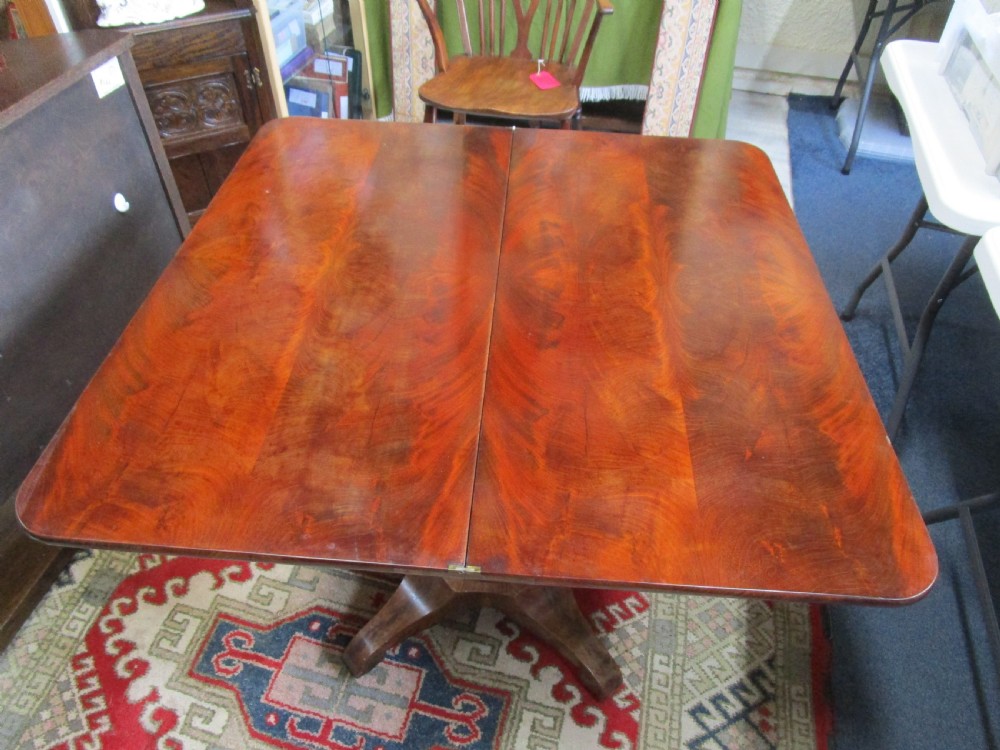 An antique timber fold-over tea table featuring a figured veneer top and a central carved pedestal base on four shaped legs. View II