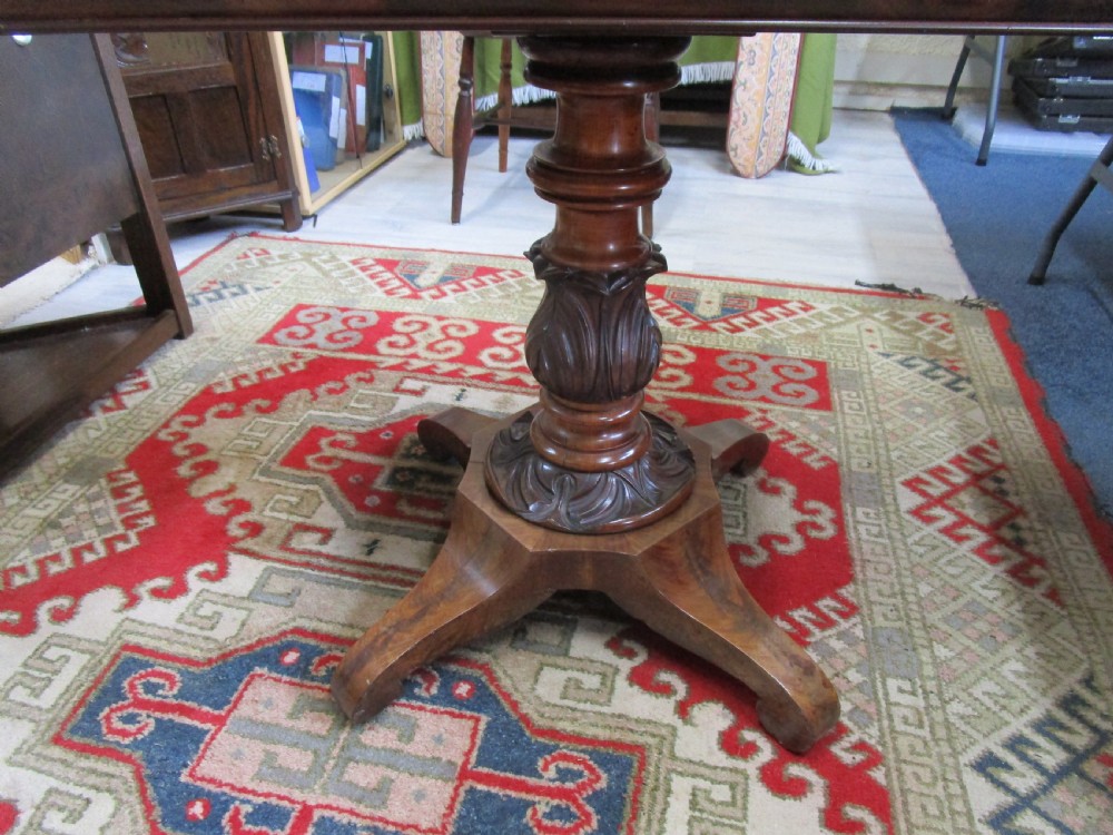 An antique timber fold-over tea table featuring a figured veneer top and a central carved pedestal base on four shaped legs. View VI