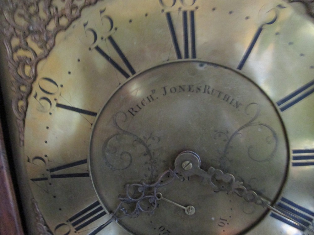 An antique dark oak longcase clock featuring a glazed hood with brass dial, slim trunk door, and plinth base. View III