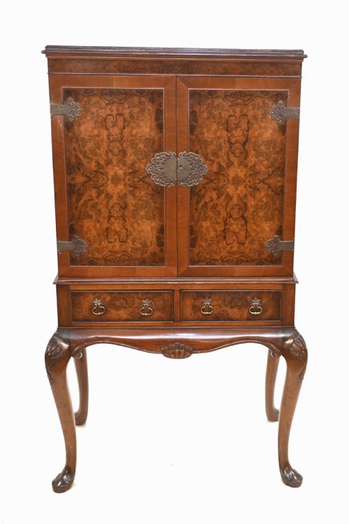fig 1. An Art Deco burr walnut drinks cabinet on a carved cabriole leg stand with ornate brass hardware and two lower drawers.